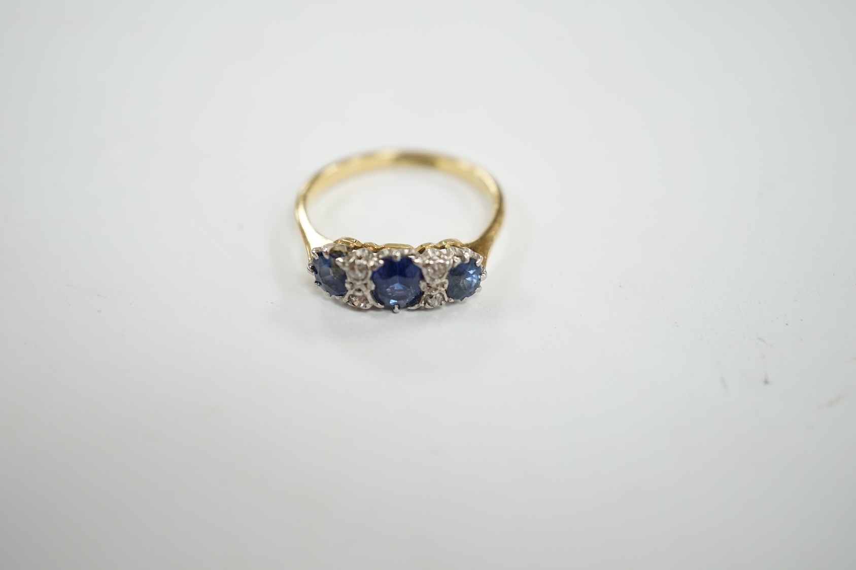 An 18ct and plat. three stone sapphire and four stone diamond chip spacer set ring, size N/O, gross weight 3.2 grams. Condition - poor to fair